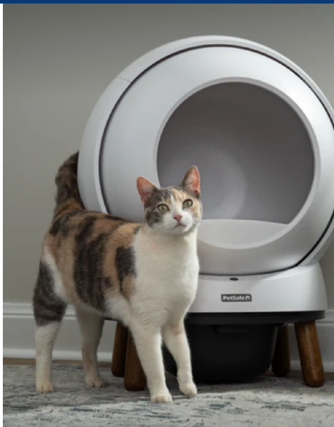 Photo of cat standing next to a self-cleaning litter box